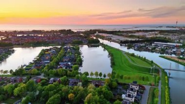 Güzel Hollanda gün batımı manzarası. Canlı günbatımı, yeşil ağaçlar ve sakin sularla dolu huzurlu Hollanda manzarası üzerinde renkli renkler oluşturur..