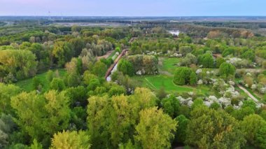 Yeşil Hollanda tarlalarının üzerinde gün batımı. Hollanda 'da hava manzarası alacakaranlıkta yeşillik, ağaçlar ve su kaynaklarının canlı bir karışımını gösteriyor..