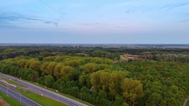 Hollanda 'nın yemyeşil manzarası. Hollanda 'da yol kenarındaki yoğun yeşilliğin sakin manzarası alacakaranlık saatlerinde doğanın güzelliğini gözler önüne seriyor..