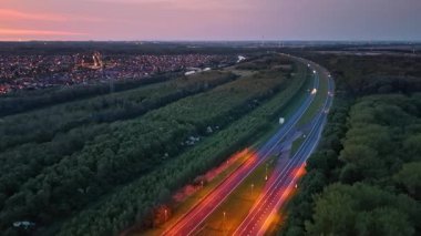 Hollanda topraklarında sakin bir yolculuk. Alacakaranlık, Hollanda 'daki yemyeşil çayırlarda dolanan ve küçük bir kasabayla çevrili huzurlu bir yolu aydınlatıyor..