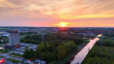 Hollanda 'nın yemyeşil manzaralı bir kasabası. Pembe gökyüzü kanalın yüzeyine yansıyor. Gün batımı manzarası. Hava görünümü.