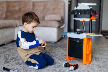Çocuk oyuncak mutfağıyla oynuyor. Küçük bir çocuk mutfak setine odaklanır, yemek pişirir ve aletleri keşfedermiş gibi yapar..