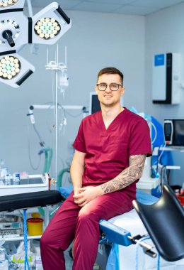 Önlüklü cerrah gevşer. Bir tıp uzmanı ameliyat masasında sakince oturur ve bir sonraki ameliyata hazırlanır..