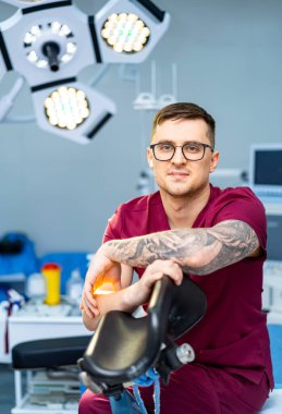 Modern dişçi sizi bekliyor. Önlüklü bir dişçi modern bir diş muayenehanesinde oturur ve iyi donanımlı bir şekilde hasta bakımına hazırdır..