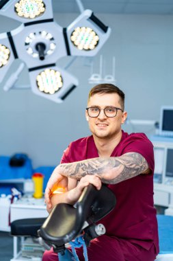 Modern klinikte cerrah hazırlığı. Gelişmiş tıbbi teknolojilerle dolu modern, temiz bir ameliyathanede bir sağlık uzmanı gülümsüyor..