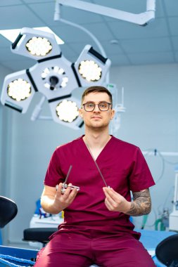 Cerrah ameliyata hazırlanıyor. Cerrahlar ameliyat odasında otururlar. Tıbbi bir prosedüre başlamadan önce cerrahi aletlerle hazırdırlar..