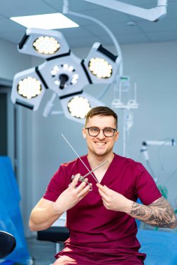 Cerrah ameliyat için aletleri hazırlıyor. Cerrah, ameliyat aletlerini parlak ve iyi donanımlı bir ameliyathanede tutarken gülümser..