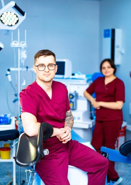 Klinik tıbbi personeli. İki sağlık çalışanı modern bir klinikte duruyor ve hasta bakımında takım çalışmalarını ve profesyonelliklerini sergiliyorlar..