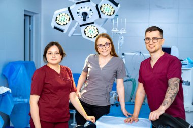 Cerrahi tıbbi personel. Üç sağlık çalışanı bir ameliyathanede takım çalışması ve uzmanlık sergileyen bir prosedüre hazırlanıyorlar..