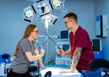 Cerrahi ekip bir prosedüre hazırlanıyor. Önlüklü cerrahlar tıbbi ekipmanlarla dolu modern bir ameliyathanede aletleri tartışıyor..