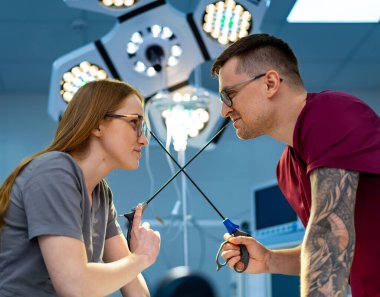 Eğlenceli sağlık hizmetleri etkileşimleri. İki sağlık uzmanı, bir cerrahi odasında makas kullanarak neşeli bir anı paylaşıyor..