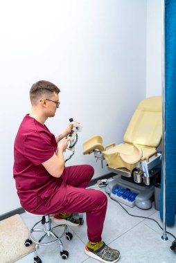 Tıp uzmanları ekipmanları kurar. Önlüklü bir sağlık çalışanı, hasta randevusu için bir klinik odasına tıbbi ekipman yerleştiriyor..