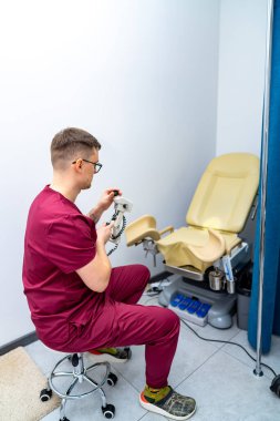 Dişçi klinikte ekipman hazırlıyor. Önlüklü bir dişçi, modern bir klinik ortamında dişçi aletleriyle hasta bakımına odaklanıyor..