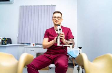 Optometrist muayene için hazır. Kestane rengi önlüklü bir erkek optometrist modern bir klinikte göz muayenesi için ekipman hazırlıyor..