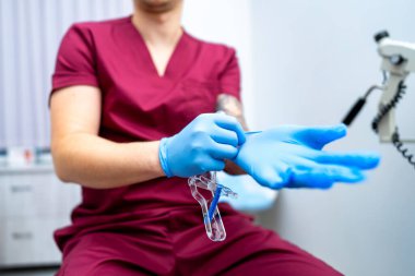 Diş muayenesi için hazırlanıyorum. Önlüklü bir diş hekimi, bir hastaya diş tedavisi yapmadan önce mavi eldiven takar..