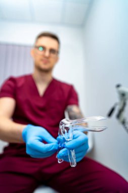 Doktor sınava hazırlanıyor. Önlüklü bir sağlık çalışanı klinik ortamda profesyonellik gösteren bir spekulum hazırlıyor..