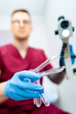 Tıp profesörü sınava hazırlanıyor. Ameliyat önlüğü giymiş bir sağlık görevlisi, bir klinikte hasta muayenesine hazırlanırken bir enstrüman tutar..