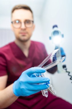 Doktor prosedüre hazırlanıyor. Önlüklü bir tıp uzmanı, klinikte ameliyat için gerekli aletleri ve ışık kaynağını bulundurur..