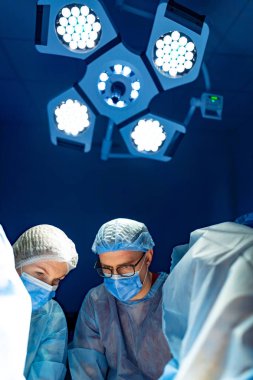 Cerrahlar ameliyatta takım olur. İki cerrah ameliyata odaklanırken parlak ışıklar ameliyathaneyi aydınlatıyor. Gerginlik havayı dolduruyor.