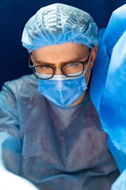 Cerrah ameliyata hazırlanıyor. Cerrahi teçhizat alanında odaklanmış bir tıp uzmanı, hastanın güvenliğini ve bakımını sağlamak için bir prosedür hazırlıyor..