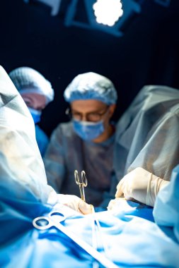 Steril odada ameliyat yapan cerrahlar. Tıp uzmanları ameliyat sırasında hastanın güvenliğini sağlamak için steril bir ameliyathanede konsantre oluyorlar..