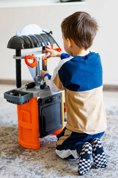 Küçük çocuk oyuncak alet setiyle oynuyor. Bir çocuk yumuşak halıdaki renkli bir oyuncakla ilgilenir, oyun oynayarak yaratmaya ve öğrenmeye odaklanır..