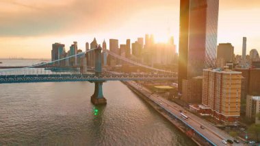 Gökdelenlerin ardında güneş batıyor. İnsansız hava aracı görüntüleri Manhattan Köprüsü 'ne yaklaşıyor. New York havası.