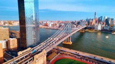 Arabalar Manhattan Köprüsü 'nden ve Doğu Nehri' nden geçiyor. İnsanlar stadyumda futbol oynuyor. Hava görüntüsü. Günbatımında New York Panoraması.