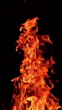 Havaya yükselen uzun kırmızı alev sütunu. Ateşten süzülen güzel kıvılcımlar. Siyah zemin. Dikey video