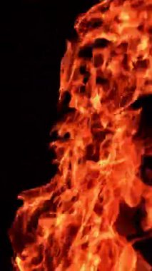 Havaya yükselen kırmızı ateş alevi. Yanan şenlik ateşi arka planda izole edilmiş. Dikey video