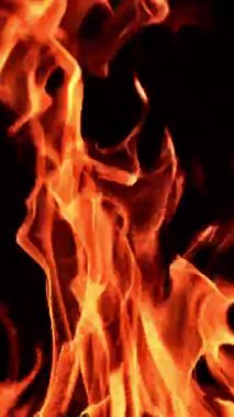 Karanlıkta yanan kamp ateşinin alevi. Alevler yükselen küçük, samimi bir şenlik ateşi. Kapatın. Dikey video