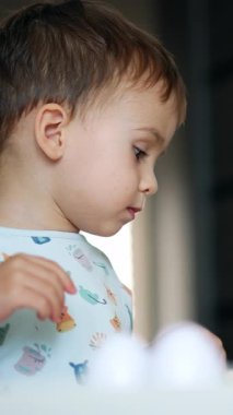 Sevimli beyaz çocuk masa başında oyuncaklarla oynuyor. Bebek bulmacalarla hayvanları öğreniyor. Dikey video