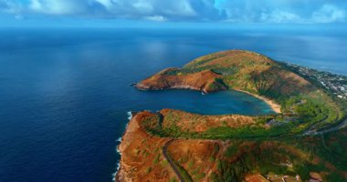 Parlak güneşle aydınlatılmış muhteşem Hanauma Körfezi 'ne yaklaşıyoruz. Mavi su manzarası ve gökyüzünün arkaplanındaki ünlü Hawaii simgesi. Hava görünümü.