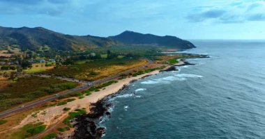 Çevresindeki dağlarla çevrili yeşil vadi boyunca otoyol geçer. Hawaii, ABD 'de Pasifik Okyanusu' nun güzel kıyıları. Hava görünümü.