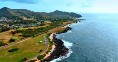 Pasifik Okyanusu kıyısında kumsalın dar bir sınırı var. Dağ eteğindeki yerleşim alanına bakın. Hawaii, ABD. Hava perspektifi.