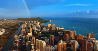 Waikiki 'nin yüksek binaları parlak güneşle aydınlatılır. Gökkuşağı arka planda Diamond Head Krateri 'ne düşüyor. Hawaii, ABD. İnsansız hava aracı görüntüleri.