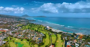 Birçok villası olan Pasifik Okyanusu 'nun inanılmaz yeşil kıyısı. Su yüzeyinin üzerinde, gökyüzünde asılı tüylü bulutlu bir manzara. Hawaii mi? ABD. Hava görünümü.