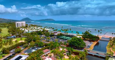 Palmiye ağaçları, park yerleri ve gayrimenkulleri olan güzel yeşil bir bölge. Honolulu, Hawaii, ABD 'deki Pasifik Okyanusu' nun resimli sahili. Su üzerinde ağır bulutlar. Hava görünümü.