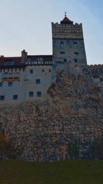 Güzel kale Bran acımasız Kont Drakula 'yı gizledi. Sonbahar doğasındaki tarihi binanın alçak açılı görüntüsü. Dikey video
