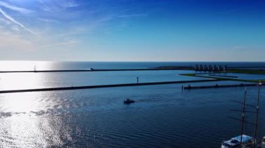 Motorlu tekne güneşli bir günde Markermeer Gölü 'nün su manzarasında yavaşça hareket eder. Arka planda uzun barajlar ve kanallar var. Hava görüntüsü. Lelystad, Hollanda.
