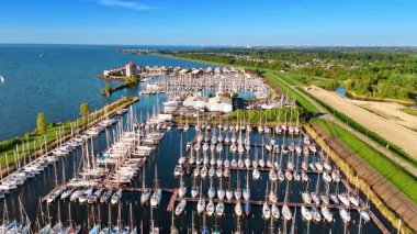 Hollanda, Lelystad 'daki Markemeer' de yat kulübünde birden fazla yat var. Yeşillikleri yemyeşil olan güzel bir göl kenarı. Hava görünümü.