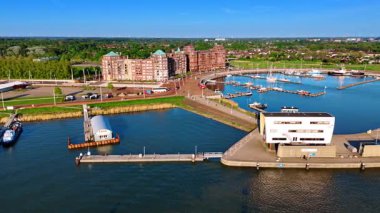 Hollanda 'nın Lelystad şehrindeki Markemeer Gölü kıyısında. Rıhtımdaki güzel binalar ve arka plandaki yemyeşil alanlar..