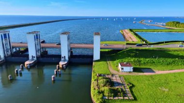 Arabalar Hollanda, Lelystad 'daki Markemeer Gölü' nün üzerindeki köprüden geçiyor. Arka plandaki mavi sudaki yatlar.