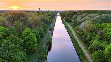 Ormanı geçen kanalın ayna yüzeyi. Güneşin battığı güzel bir gökyüzü.