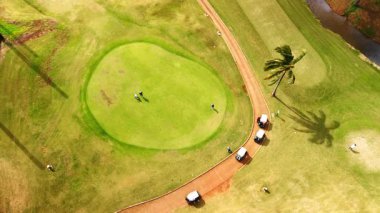 Sahada golf oynayan üç adam var. Hawaii, ABD 'deki golf sahasına hava perspektifi.