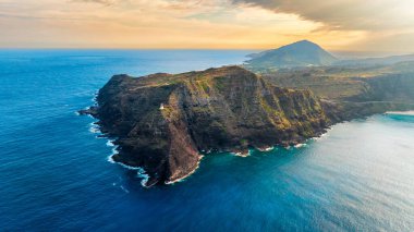 Güçlü kayalar Pasifik Okyanusu 'nun huzurlu mavi sularını kesiyor. Arabalar dağın sınırlarını çizen otoyolun yanından geçiyor. Hawaii, ABD. Hava görünümü.