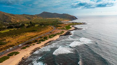 Okyanus karayla buluşuyor. Sahildeki çıplak kayalar dalgalarla kıvrılmış. Oahu kıyısı, Hawaii, ABD. Hava görünümü.