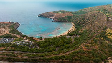 İnsanlar Honolulu, Hawaii, ABD 'deki Hanauma Körfezi' ndeki kumlu plajda dinleniyor. İnsansız hava aracı gündüz vakti çarpıcı bir dönüm noktasında uçuyor..