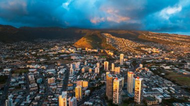 Honolulu, Hawaii, ABD 'nin çeşitli şehirlerinden aşağı iniyor. Dağların üzerinde kara bulutlar asılı..