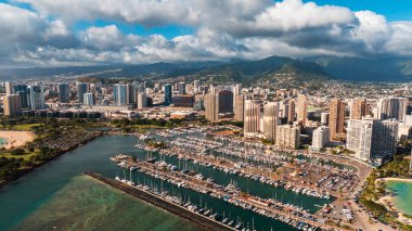 Waikiki rıhtımındaki çapada bir sürü yat duruyor. Bulutlu gökyüzünün altında güneşli bir Honolulu, Hawaii manzarası. Hava görünümü.